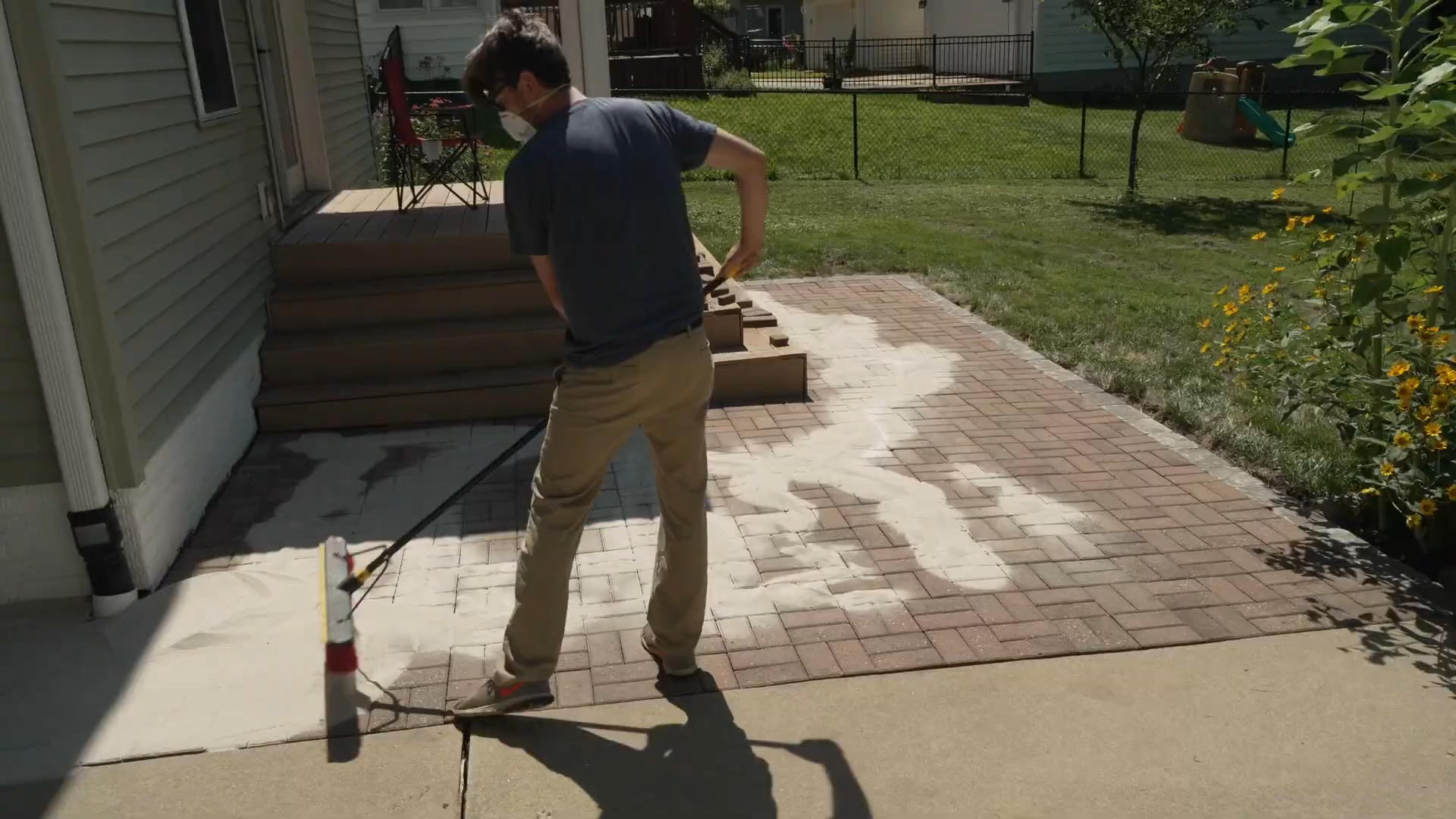 man spreading sand over joints with a floor broom